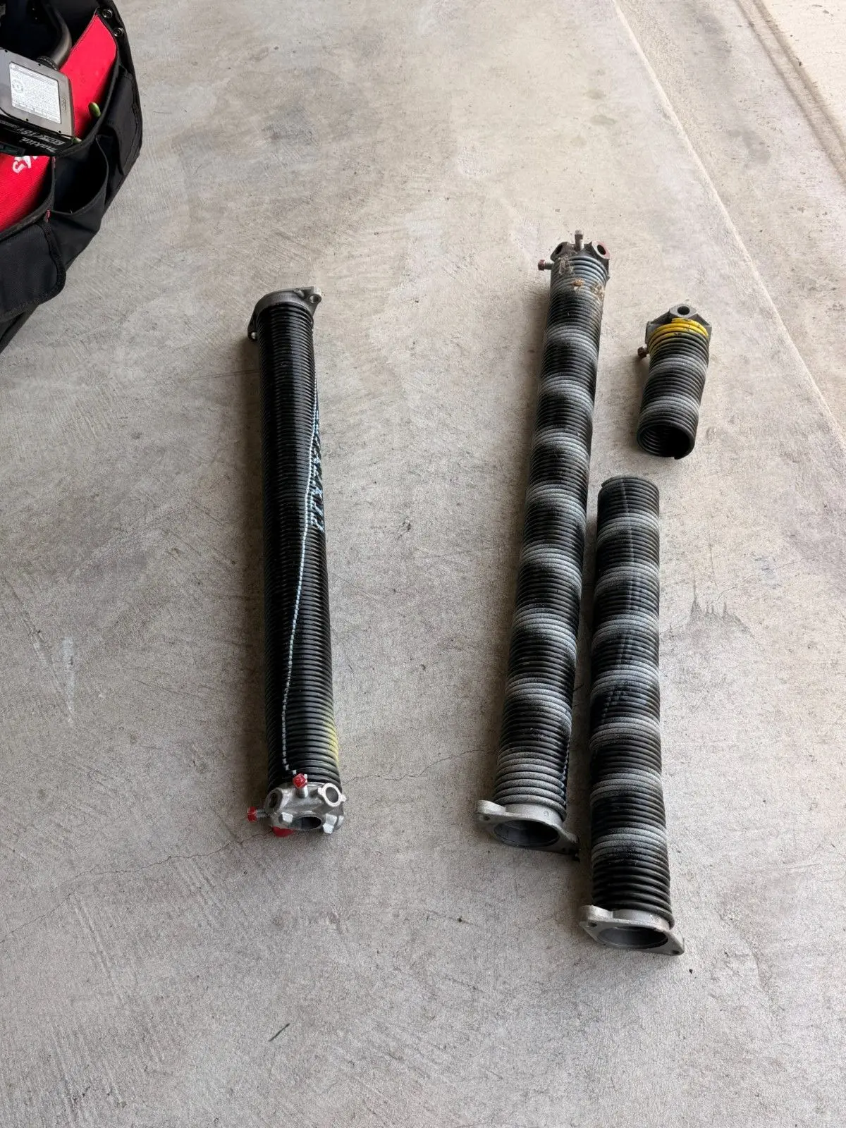 Two broken garage door torsion springs laid on a garage floor after removal