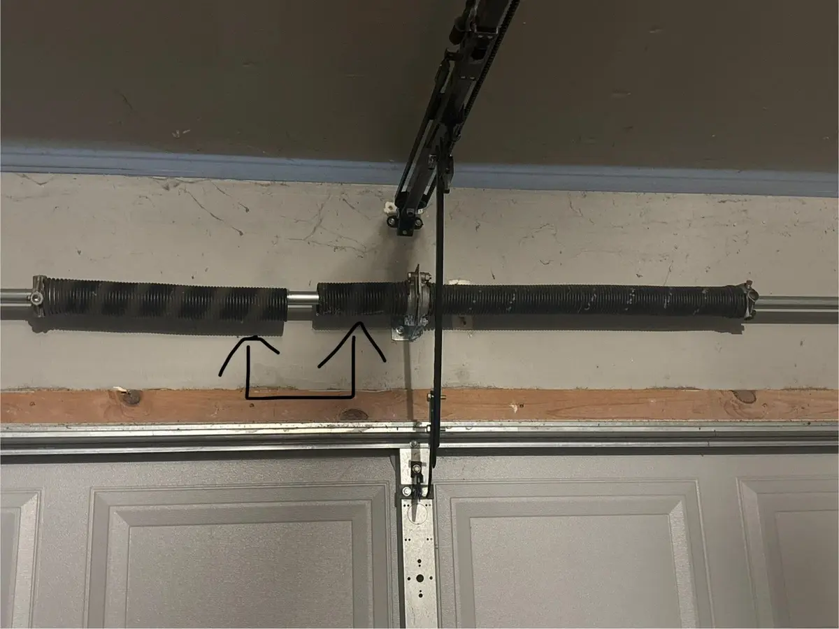 Broken torsion spring above a garage door, showing a gap in the coil