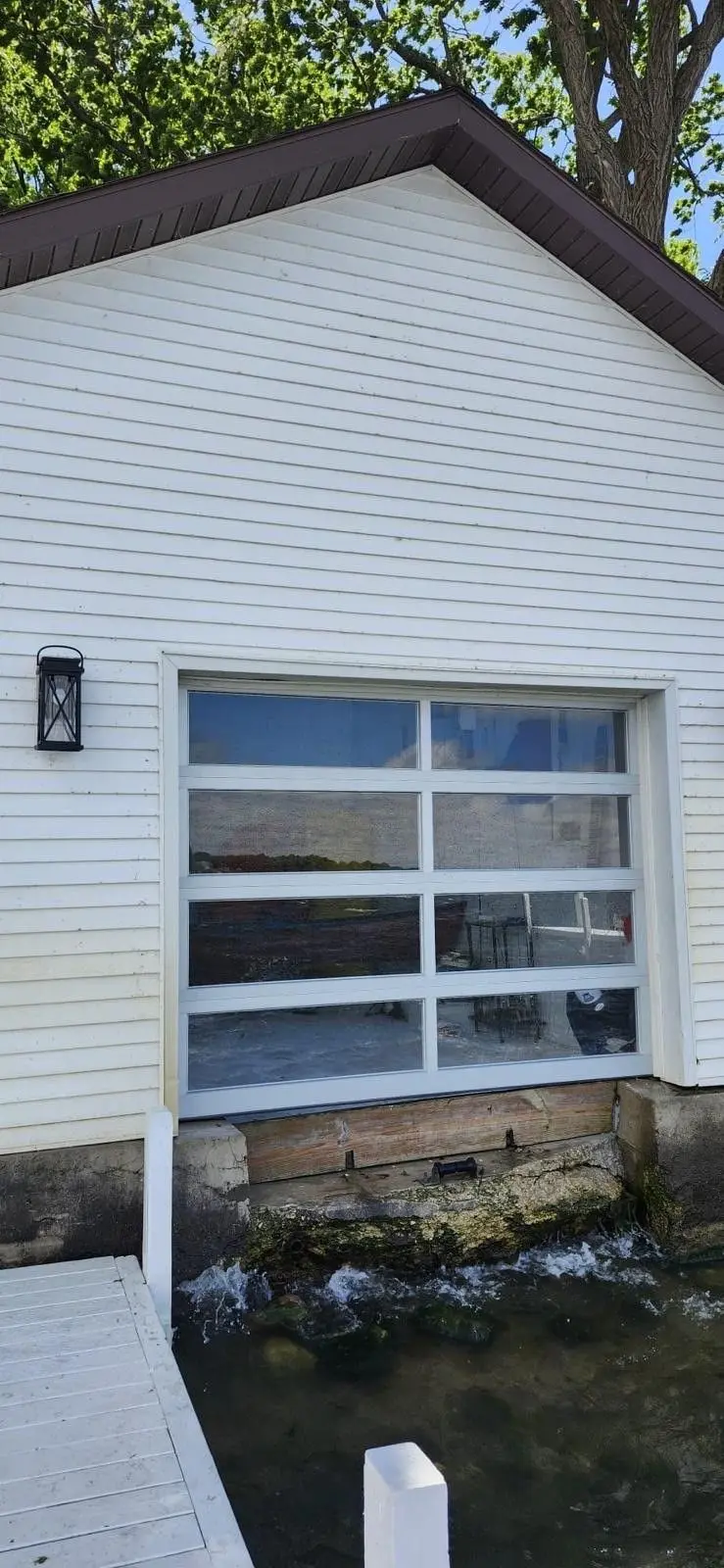White framed full view glass garage door on a white sided building
