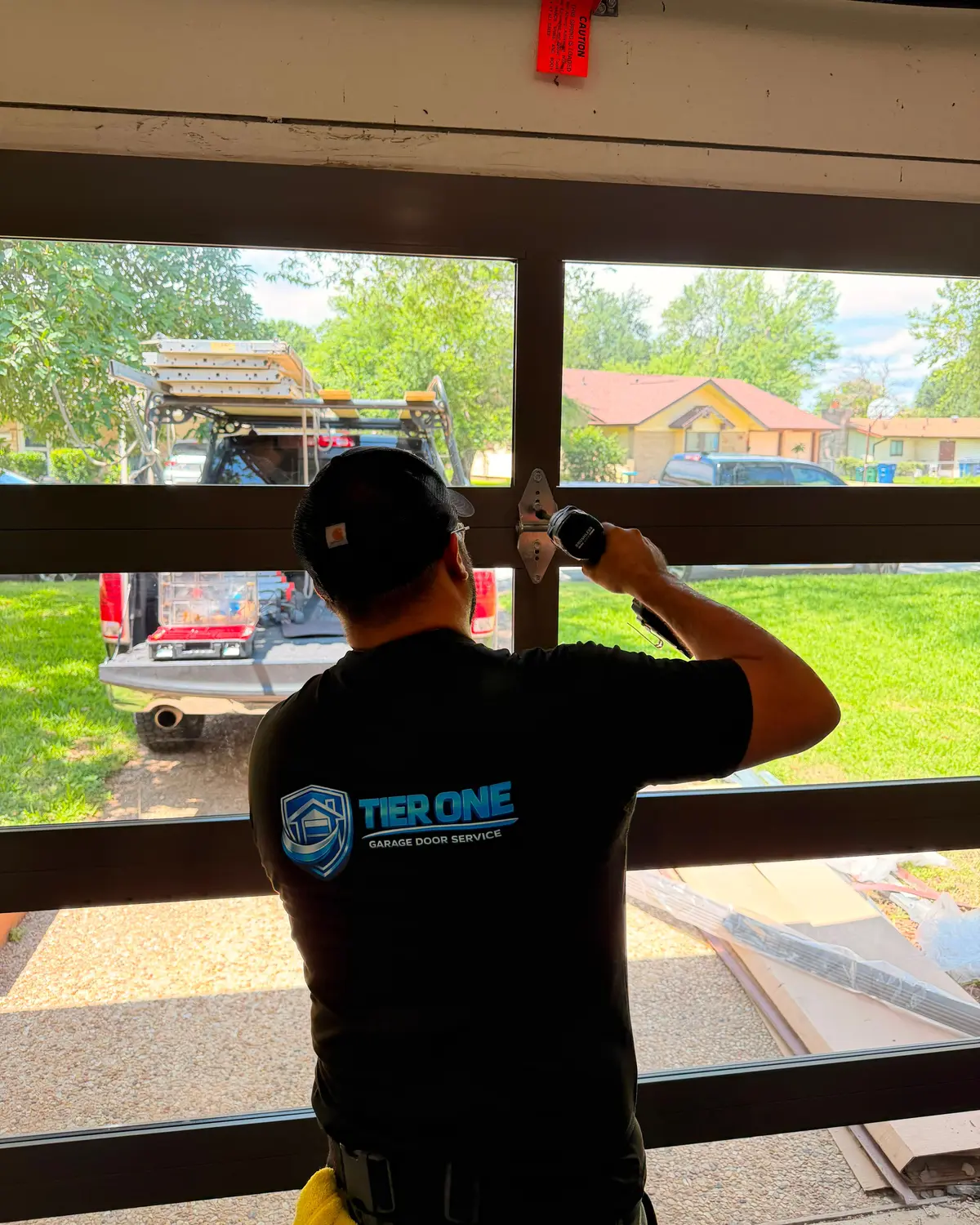 Tier One technician fitting a section of a full view glass garage door