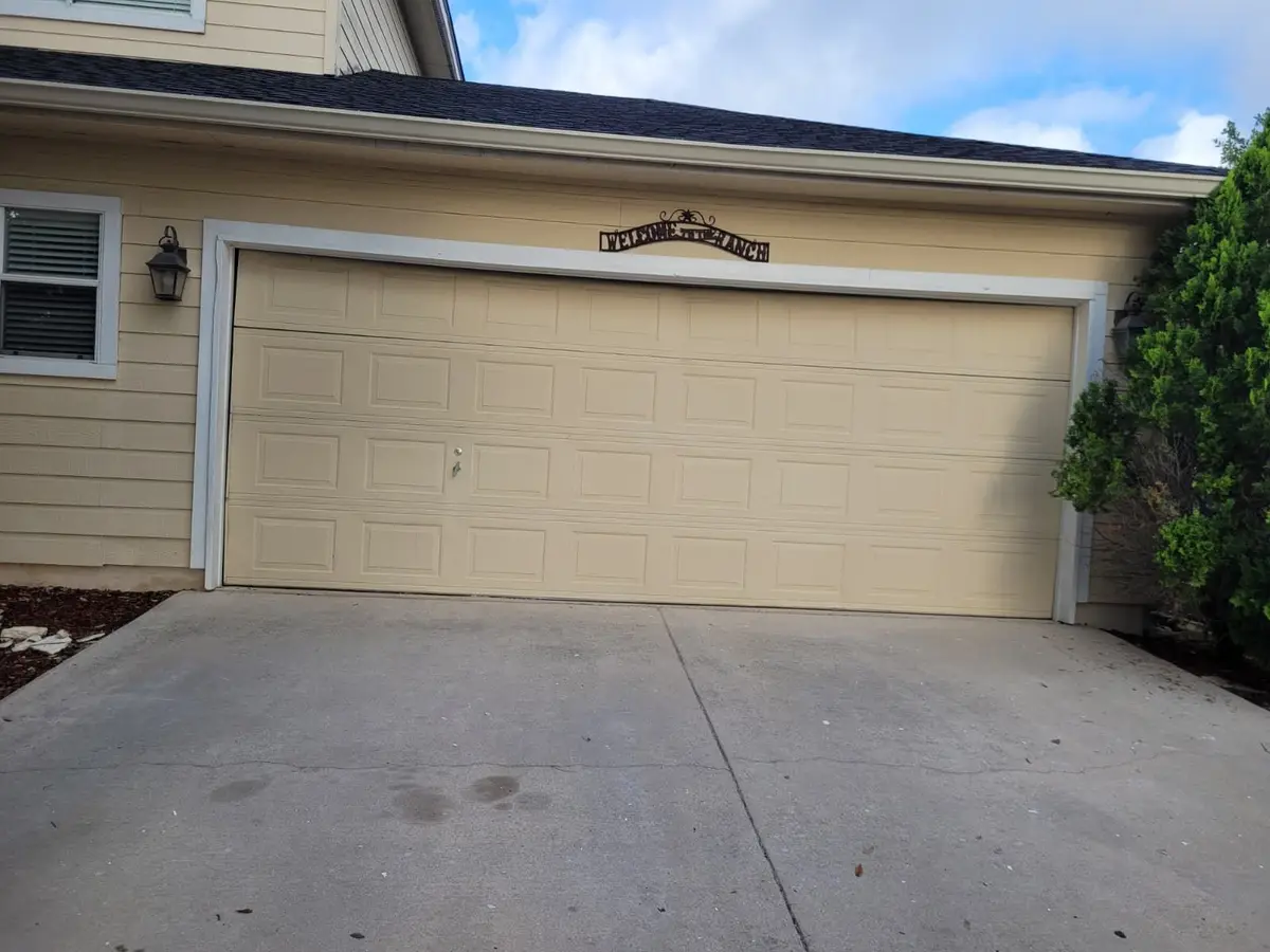 Before: almond double garage door on a home with yellow siding