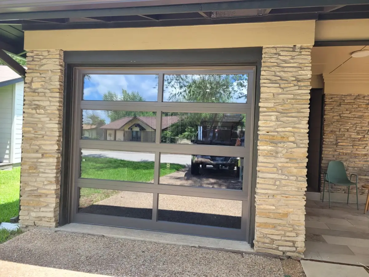 Bronze framed full view glass garage door on a stone fronted Austin home, installed by Tier One