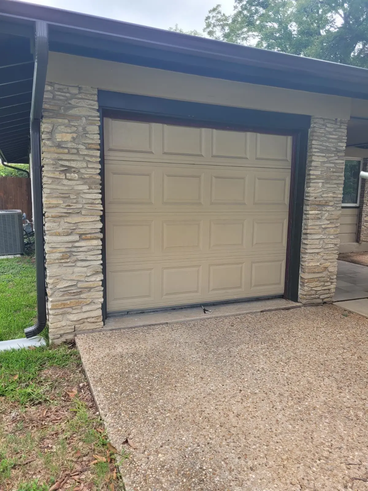 Before: almond raised panel single garage door on a stone fronted Austin home