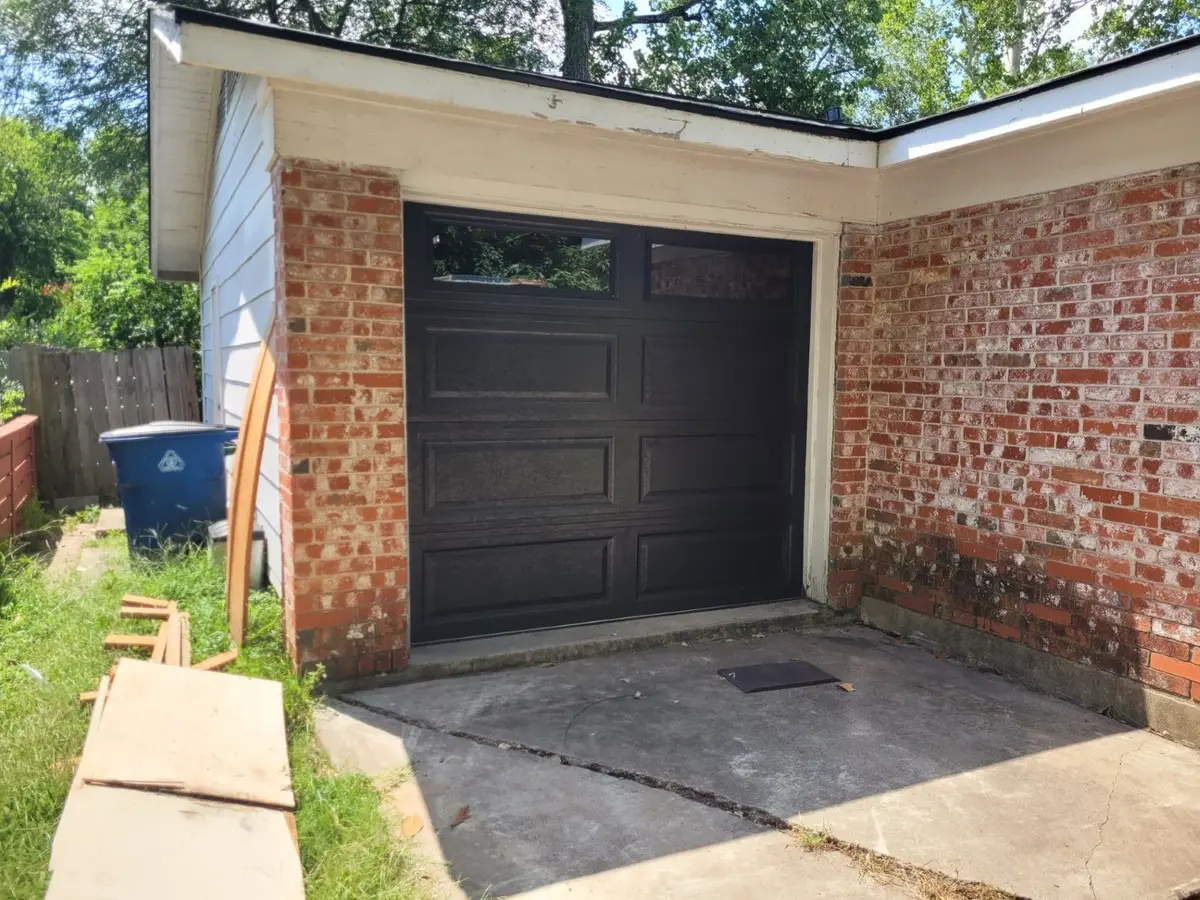 Dark raised panel single garage door on a brick garage, installed by Tier One