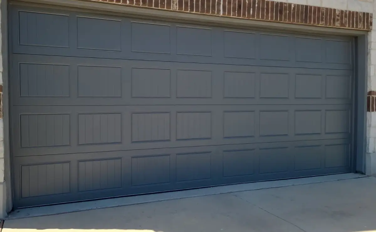 Charcoal carriage style double garage door installed by Tier One on a stone and brick Buda home
