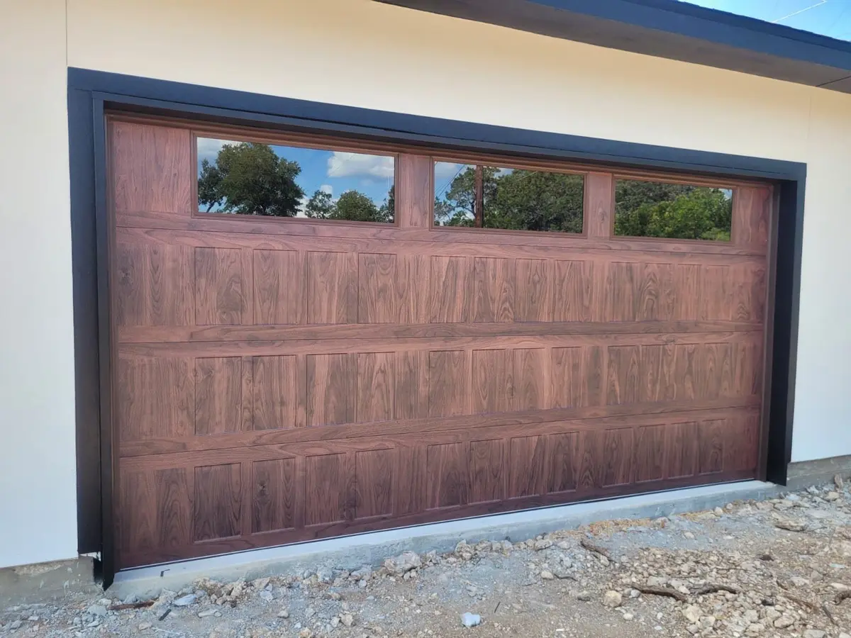 Close-up of a wood tone garage door with three windows and black trim, installed by Tier One