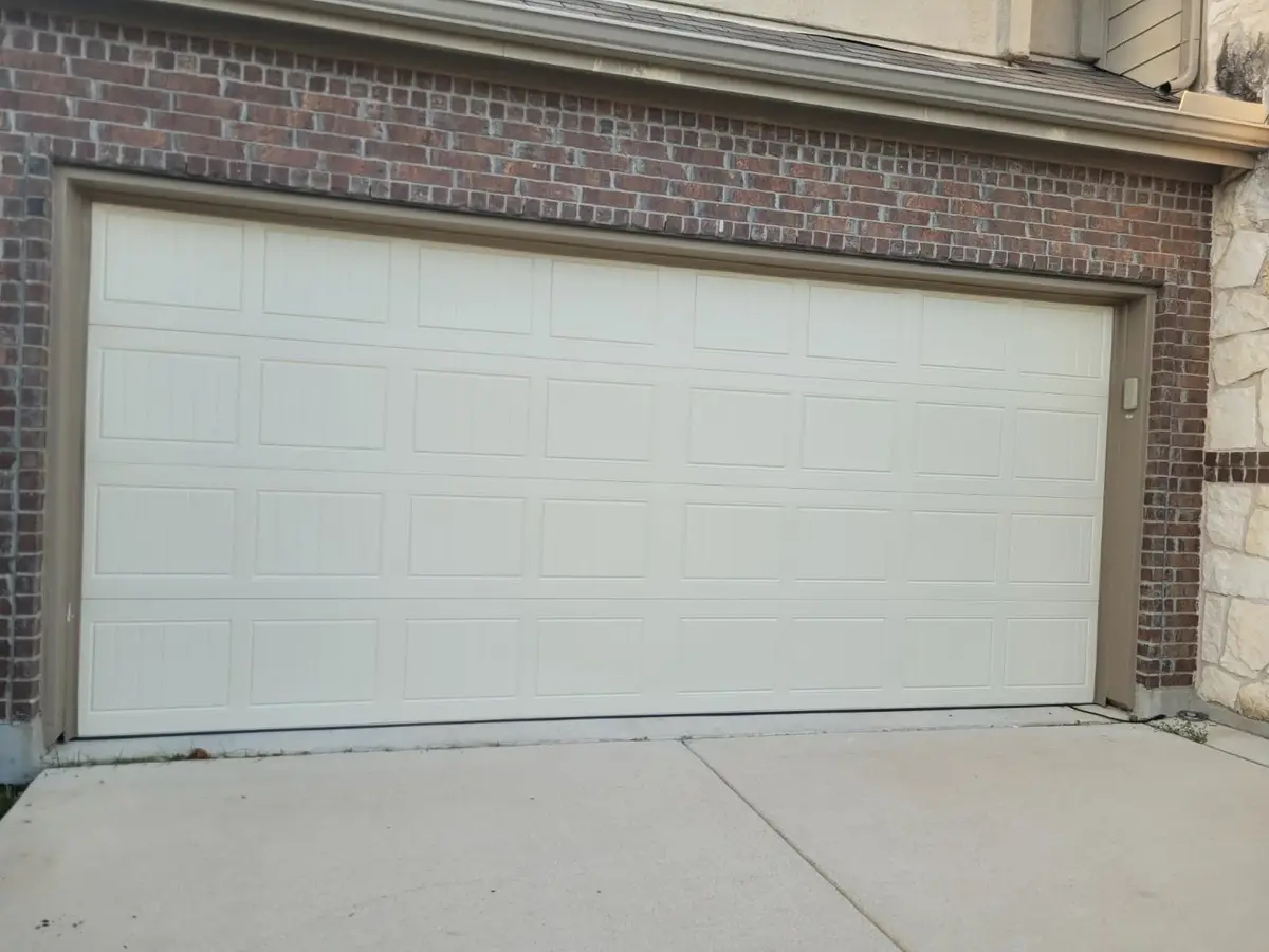 Insulated almond grooved panel garage door on a brick Hutto home, installed by Tier One