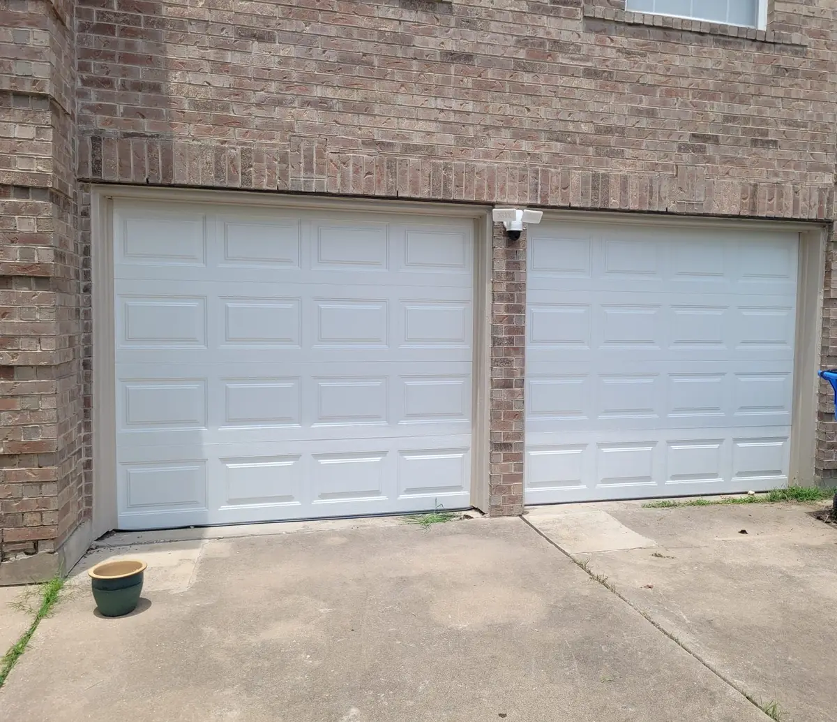 After: two new white raised panel single garage doors installed by Tier One in Pflugerville