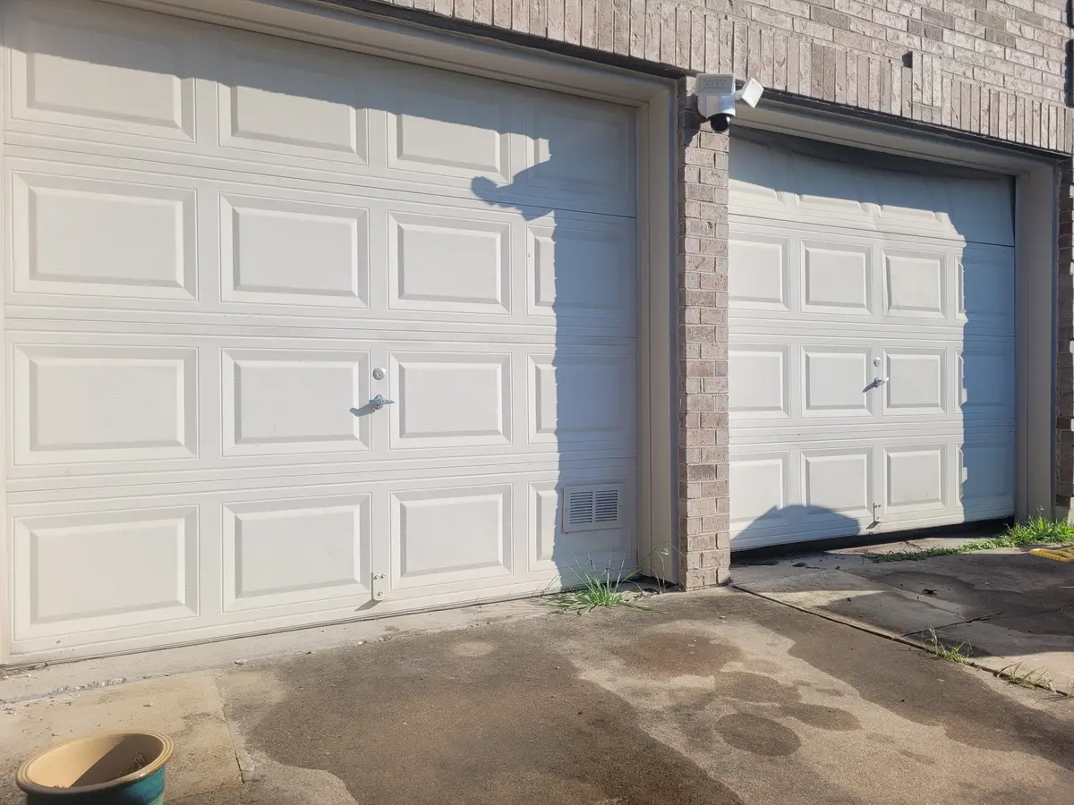 Before: two original white single garage doors on a brick Pflugerville home