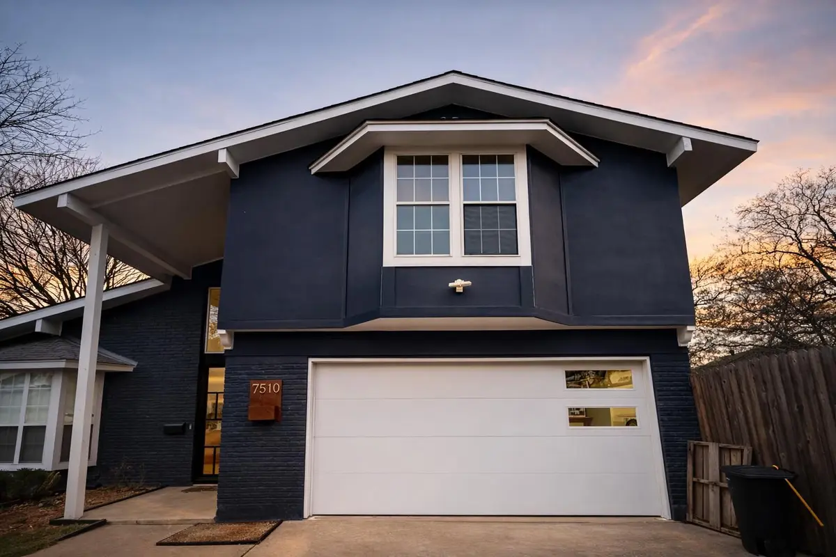 White flush panel garage door with offset windows on a dark blue home, installed by Tier One
