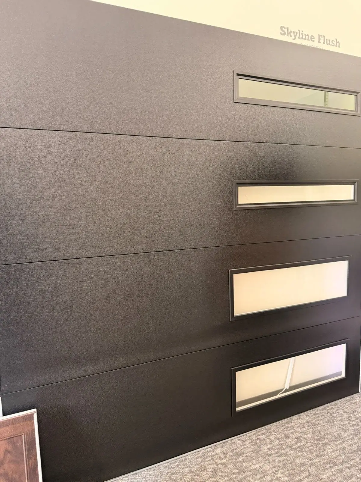 Showroom sample of a black modern garage door with slim offset windows