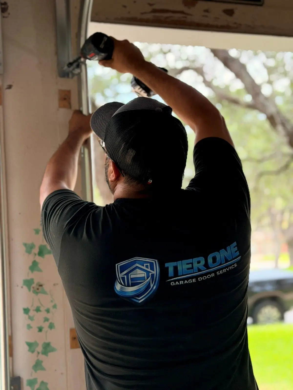 Tier One technician reaching up to fit a garage door track