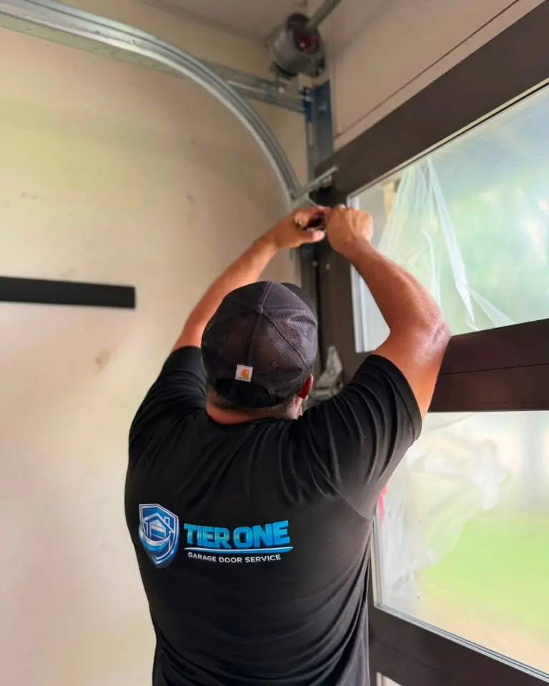 Tier One technician inspecting the horizontal track and hardware of a garage door